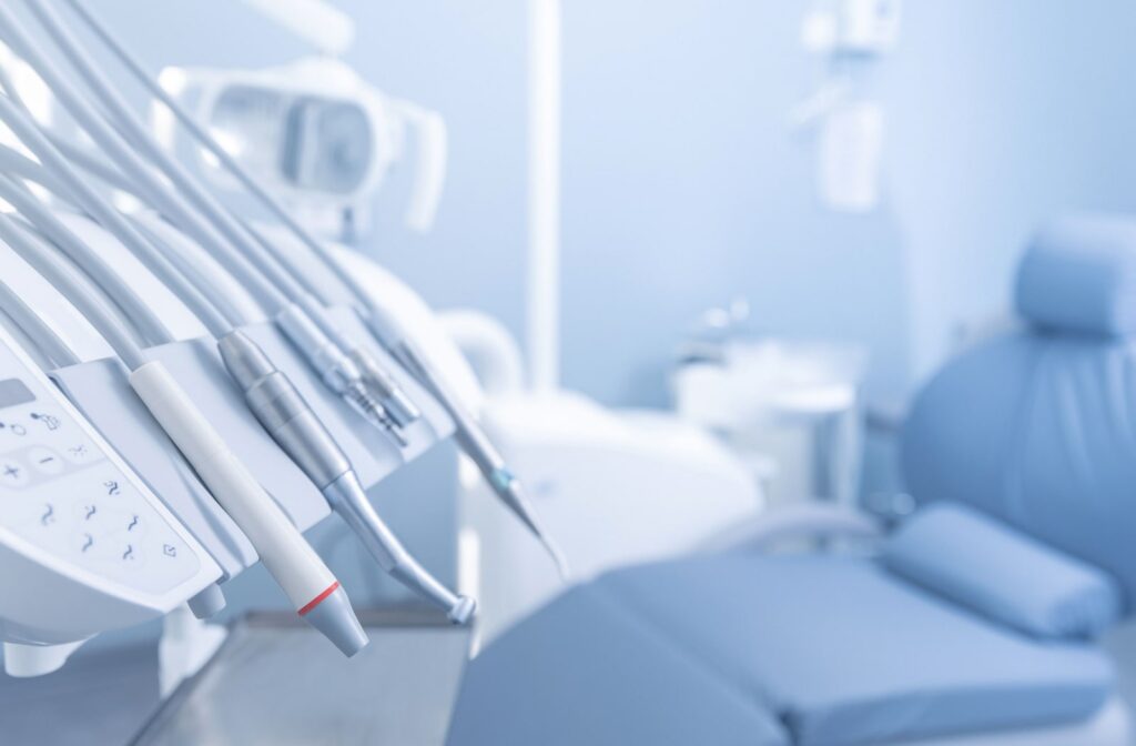 Several dental tools sitting out and an empty dental chair is in the background out of focus