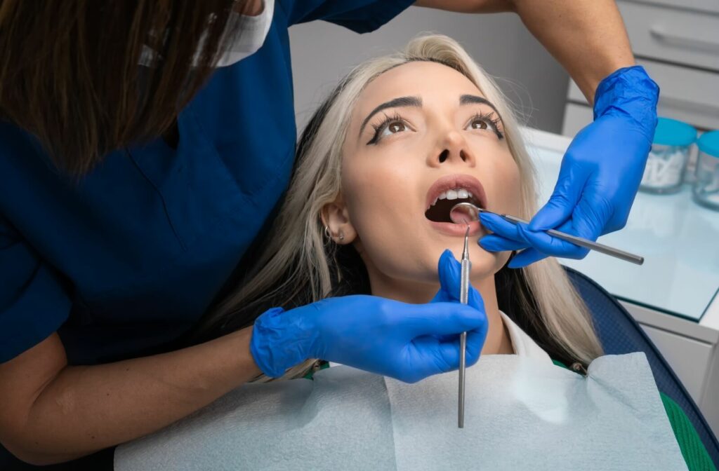 A young woman at the dentist being inspected for a cavity.