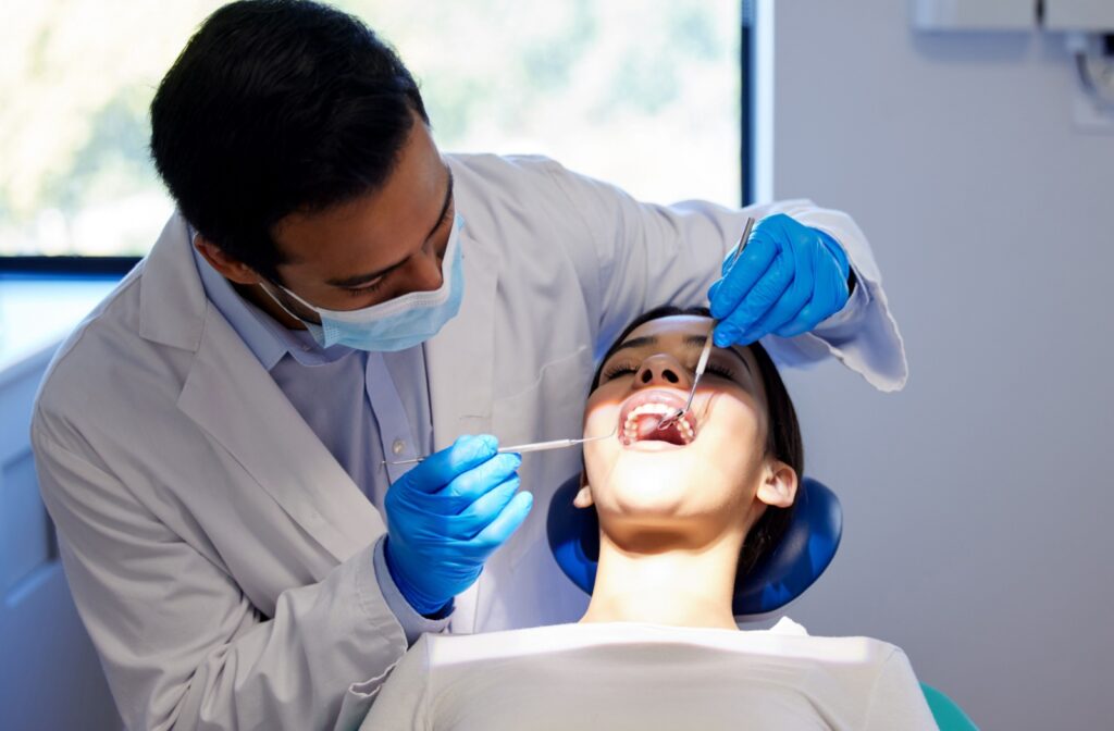 A dentist performs a thorough examination of their patient's mouth as part of a routine dental recall exam.