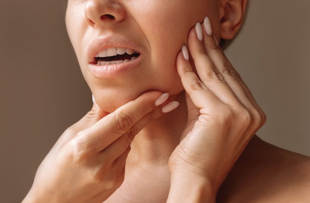 A dental patient rubbing their jaw in discomfort after trying to eat after a tooth filling was installed.