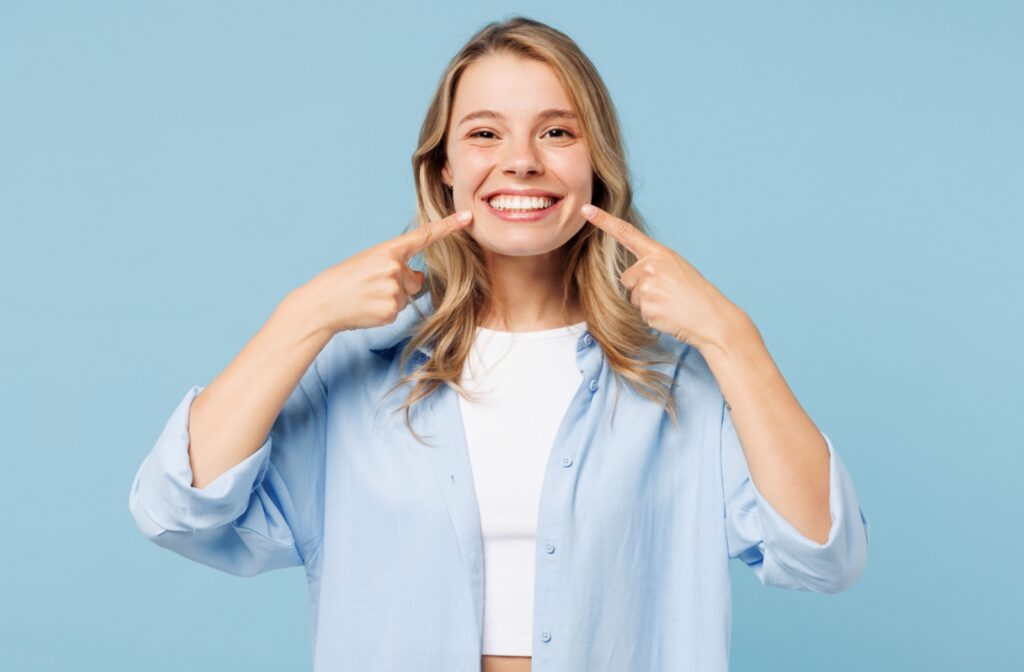 Patient smiling and pointing to their teeth after a professional whitening treatment.