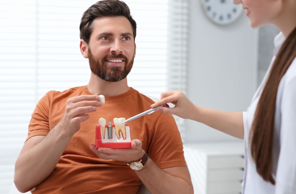 Person learning about dental implants with dentist using a model during consultation.