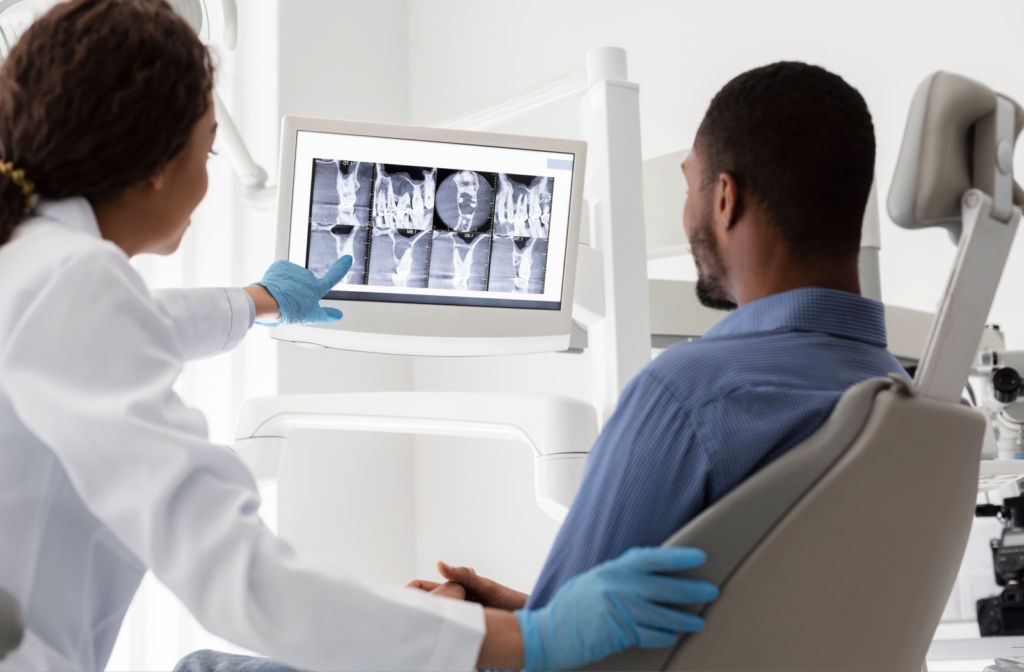 Dentist pointing at X-rays to a patient during a dental exam.